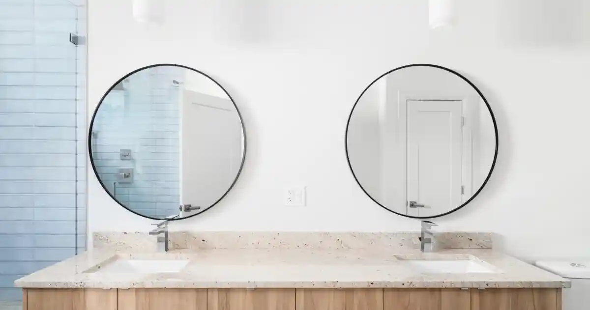 A bathroom with a wood cabinet and circular mirrors.