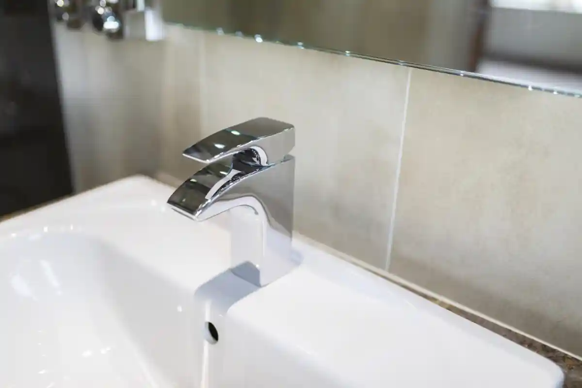 A close up of a shiny chrome modern tap in the bathroom of a luxury hotel