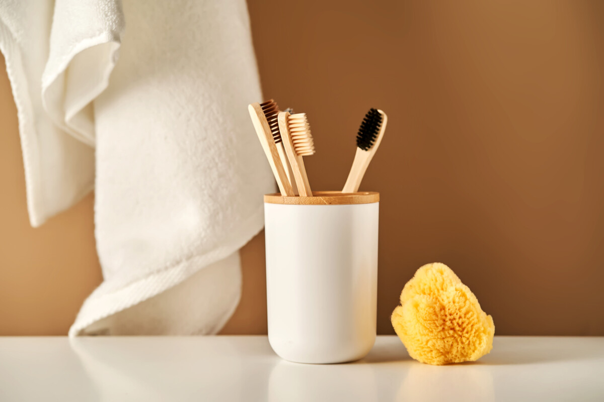 Bamboo toothbrushes in a cup and a towel in a bathroom interior.