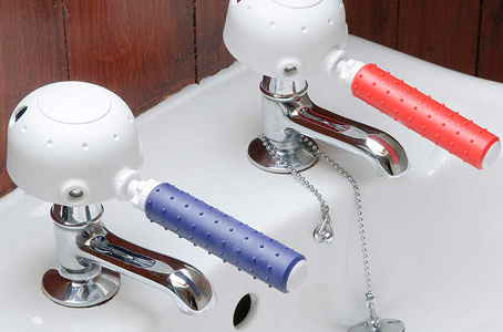 Easy-turn tap adaptors with red and blue grips fitted to bathroom sink taps for improved accessibility.