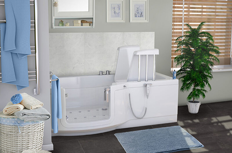 Modern bathroom with a walk-in bath featuring an integrated powered seat, positioned beside soft blue towels and a potted plant.