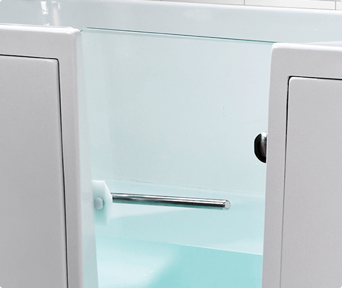 The image shows the walk-in door of the Hampton Elite bath, featuring a clear, inset door with a white frame and aqua-tinted water visible inside. The bath’s clean lines and accessible design highlight its user-friendly features.