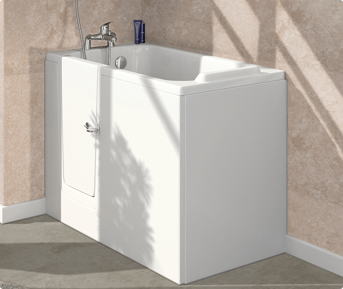 Image of the Hampton walk-in bath, featuring a white design with an inward-opening door. The bath is positioned against a cream textured wall, with sunlight casting soft shadows on its surface. The interior includes a built-in seat and modern chrome taps with a handheld shower attachment.