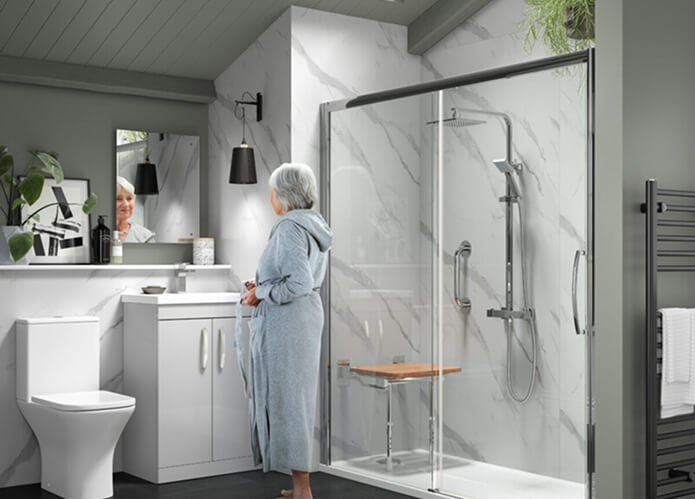 Contemporary bathroom with a Richmond sliding door shower, featuring a fold-down seat and grab rails, beside a woman in a robe standing at the sink.