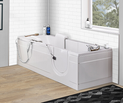 The Leyburn walk-in bath with low-level door and moulded seat, set against white subway tiles with a wood-effect floor and window view.