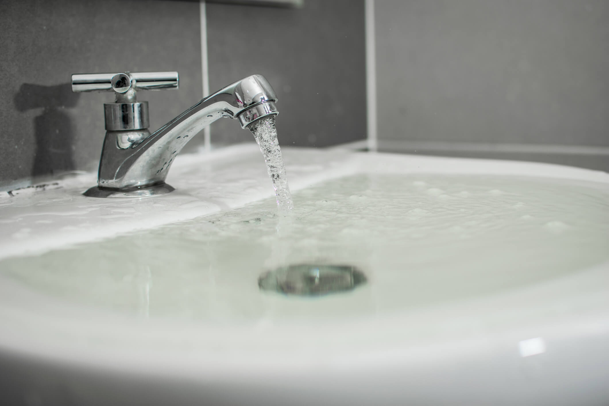 A blocked sink over flowing with water.