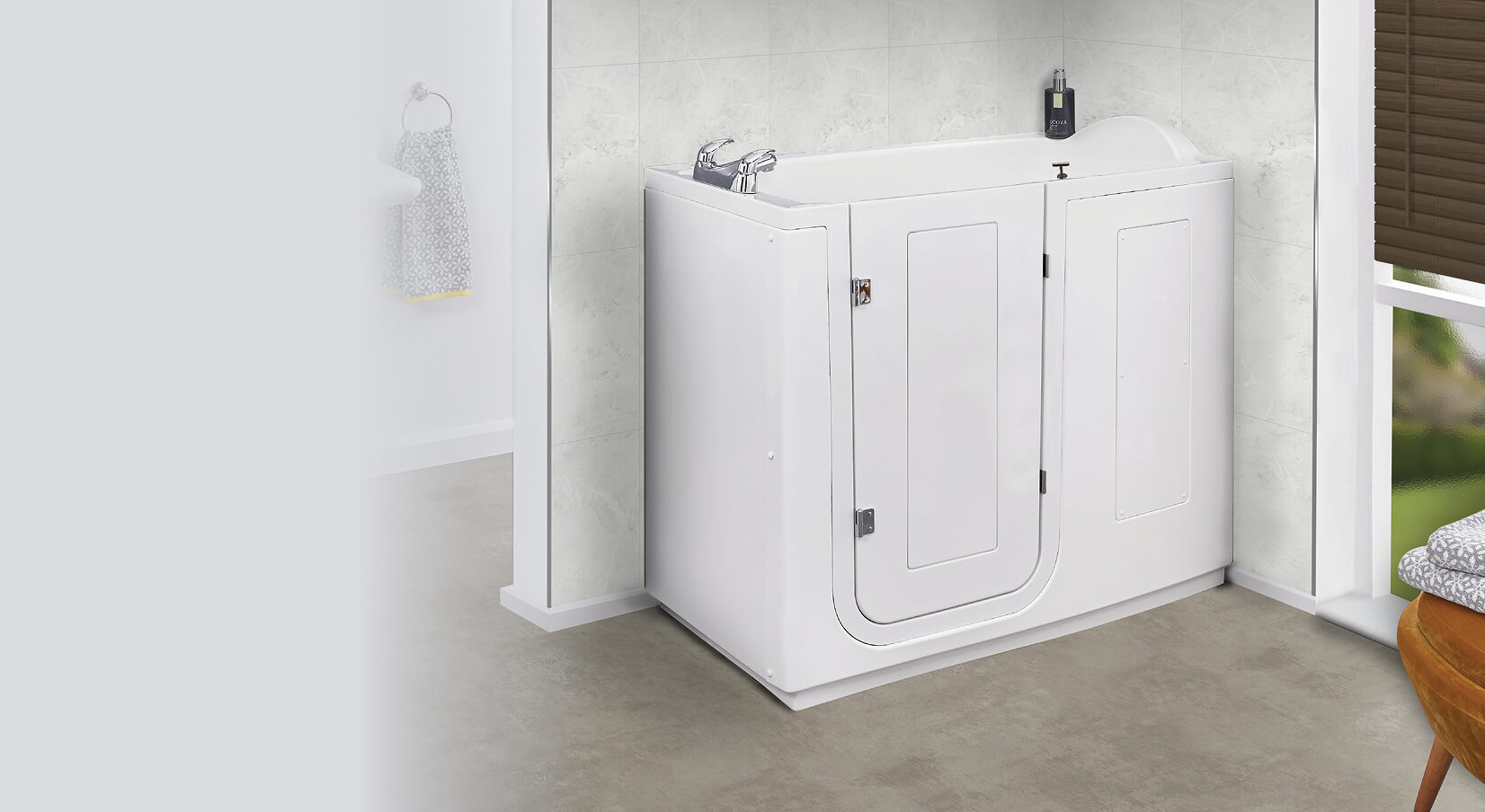 White walk-in bathtub named Grasmere installed in a bathroom corner. The tub features a side-opening door with a secure locking mechanism, chrome taps, and a sleek modern design. The background shows light marble walls, a window with blinds, and a cozy chair nearby.