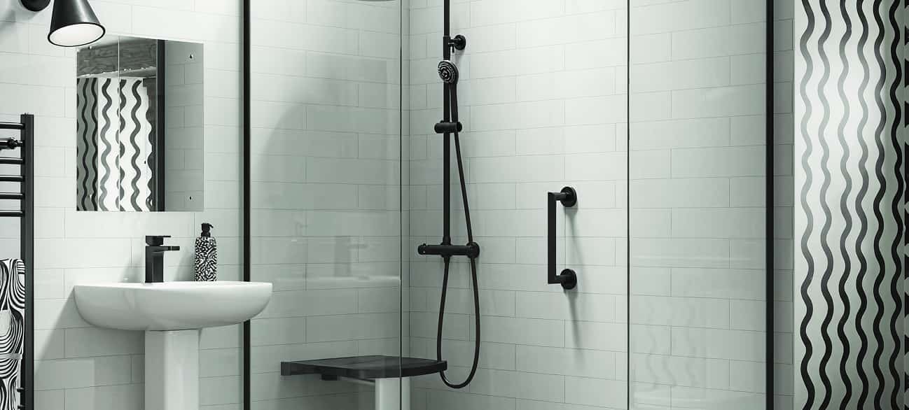 Walk-in shower with black wall-mounted seat, vertical and horizontal grab bars, and handheld shower. Pedestal sink nearby.