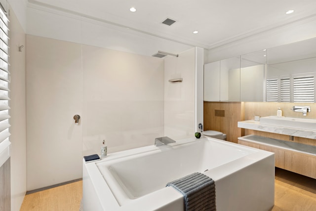 Stone effect bathroom tiles in a light airy bathroom with a bath