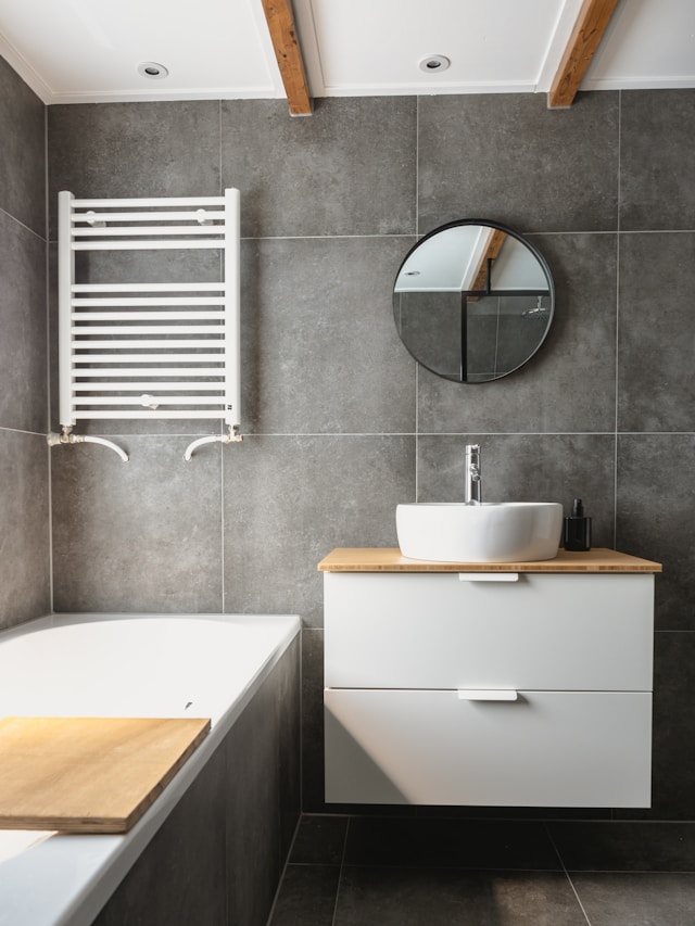 Dark grey large bathroom tiles with a white towel rail